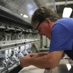 Bruce Pullan operating the quilter and meticulously threading a needle.