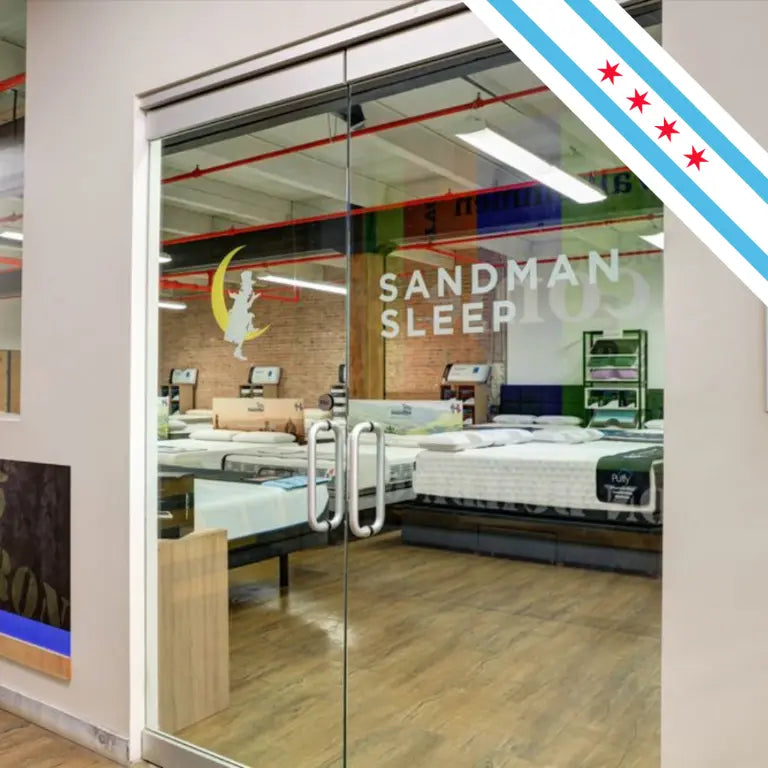Looking through the doors at mattresses of the Sandman Showroom in Illinois with a Chicago flag in the corner.