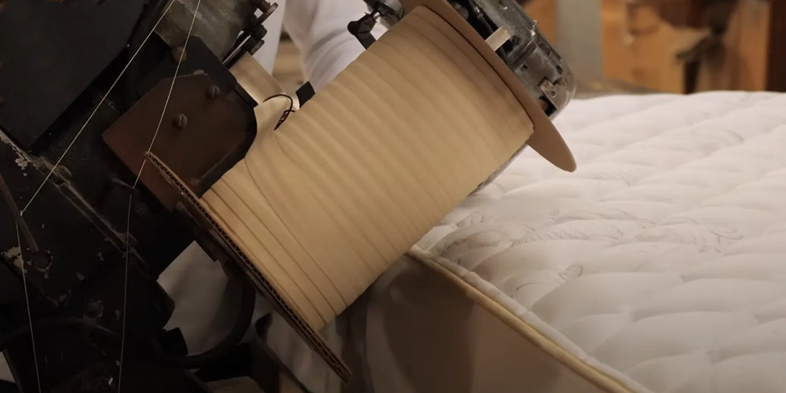 Tape edging a mattress in the factory.