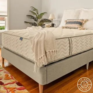 DLX Mattress on a platform bed, complete with blankets and pillows, showcasing the 120-night risk-free trial logo.