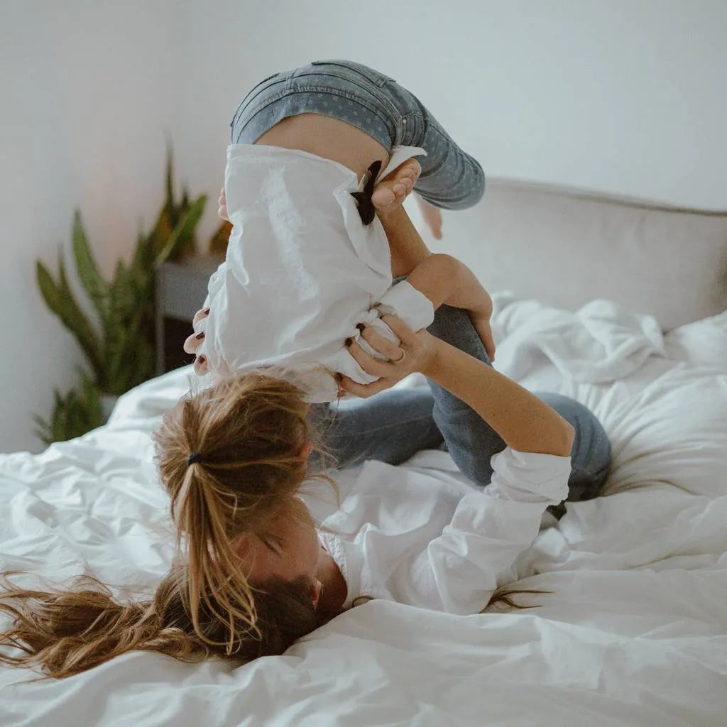 Joyful family playing on a DLX mattress. Join our mission: Each DLX mattress bought aids in giving back to the community.