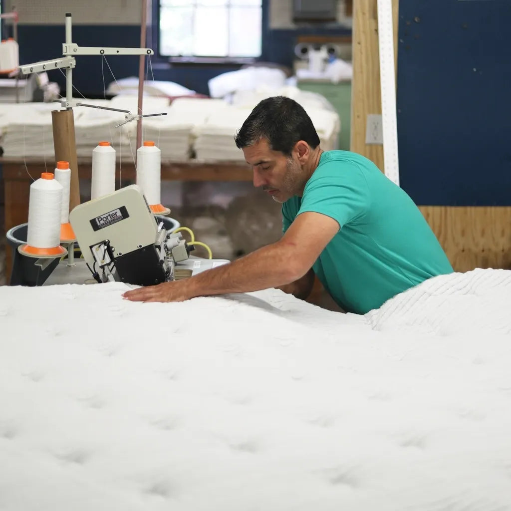 Craftsman flanging a quilted mattress cover, showcasing DLX's attention to detail.