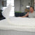 Artisan upholstering a DLX mattress with foam and a quilted cover, fiberglass-free for superior quality.