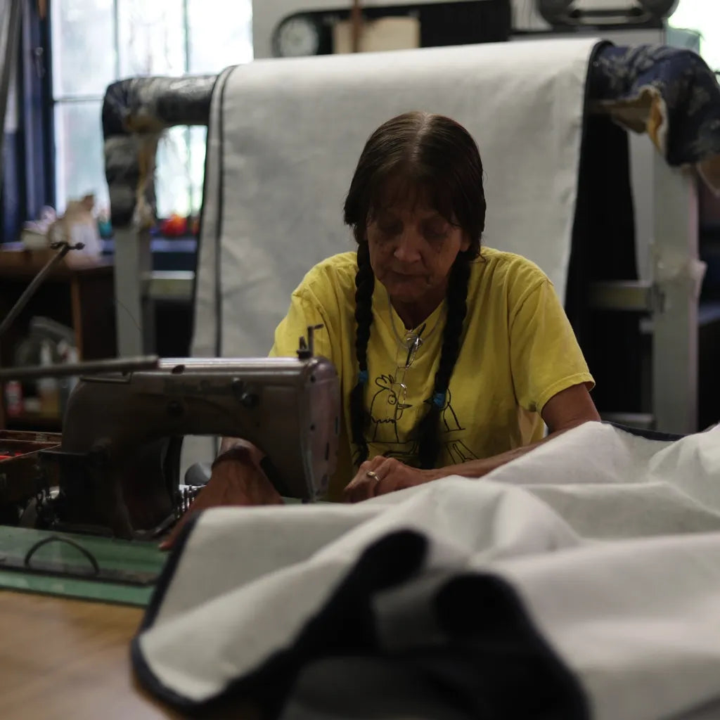Dedicated craftswoman sewing a premium DLX mattress cover, highlighting the brand's craftsmanship.